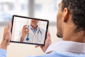 Man talking to doctor on tablet during virtual telemedicine visit