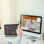 Man sitting in front of a computer talking to a doctor via video chat.